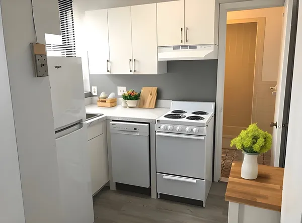 a room with stainless steel appliances white cabinets and wooden floor