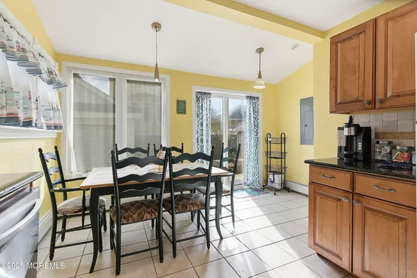 a dining hall with stainless steel appliances kitchen island granite countertop a table chairs and granite counter tops