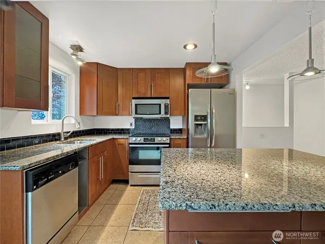 a kitchen with stainless steel appliances granite countertop a sink stove and refrigerator