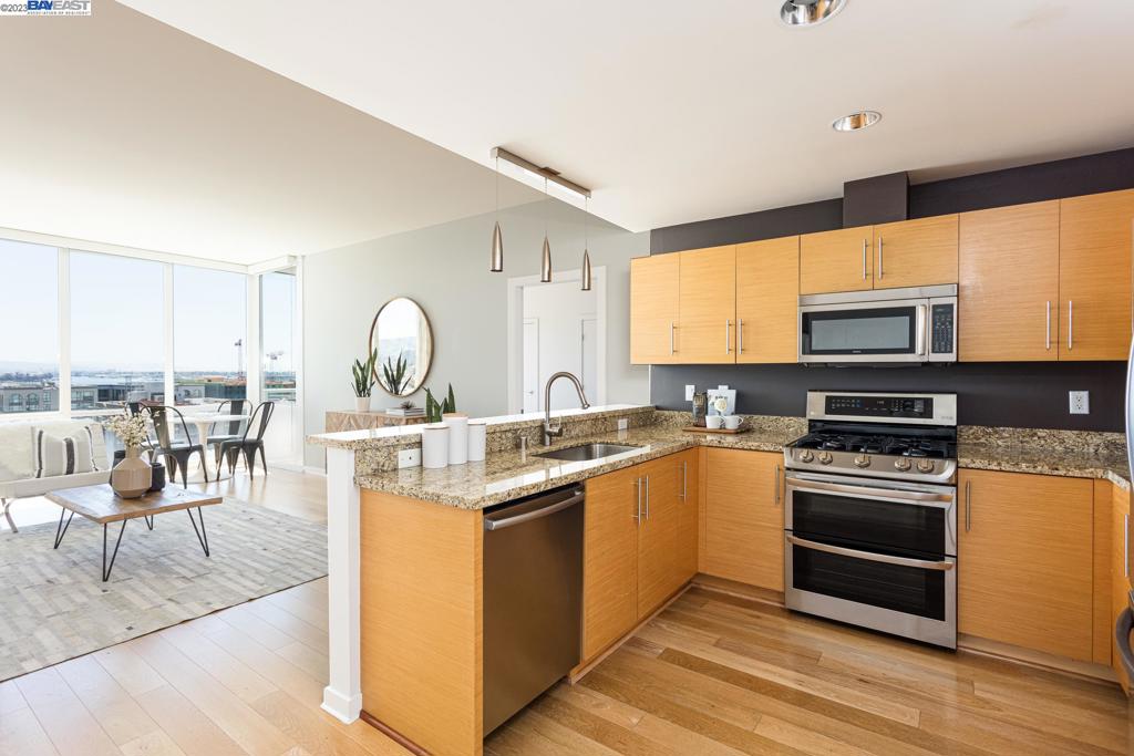 a kitchen with stainless steel appliances granite countertop a stove top oven a sink dishwasher a dining table and chairs with wooden floor