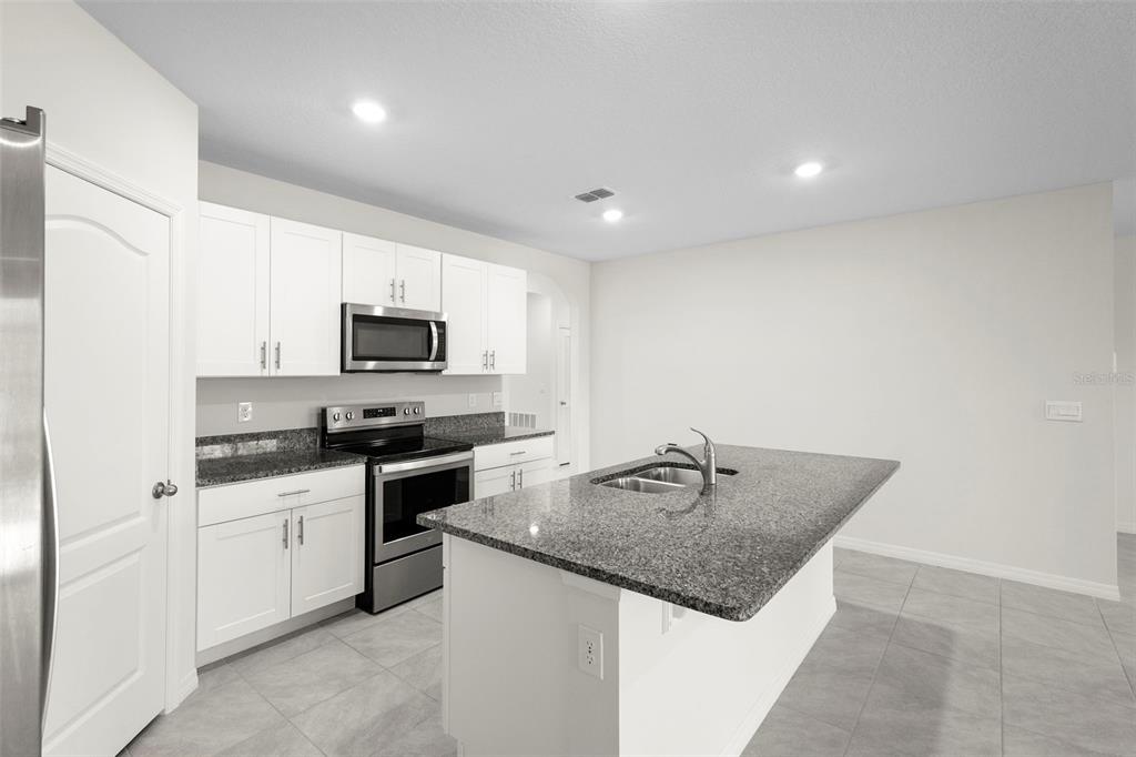 336 Camilla Road DeLand, FL 32724 - Photo 16 of 38 a kitchen with granite countertop a sink stainless steel appliances and white cabinets