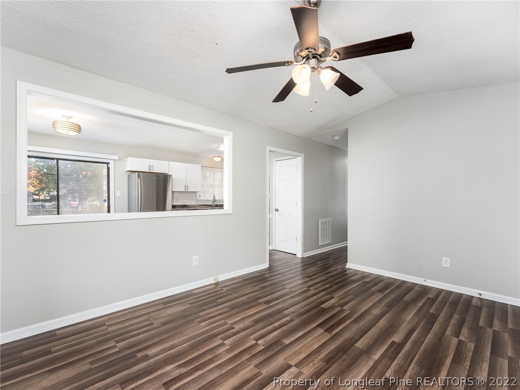 921 Hollydale Lane Fayetteville, NC 28314 - Photo 11 of 32 an empty room with wooden floor chandelier fan and windows