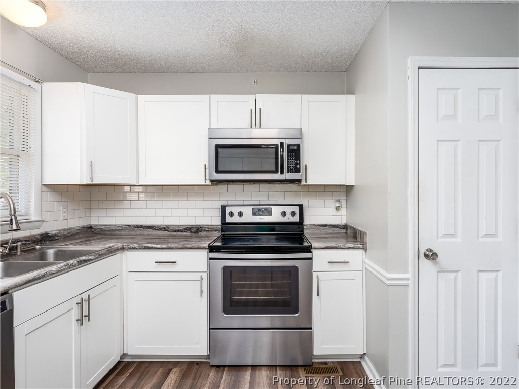 921 Hollydale Lane Fayetteville, NC 28314 - Photo 14 of 32 a kitchen with white cabinets and stainless steel appliances