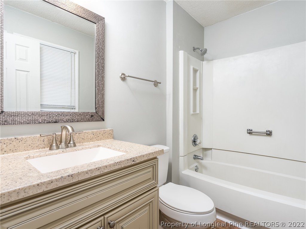 921 Hollydale Lane Fayetteville, NC 28314 - Photo 21 of 32 a bathroom with a granite countertop toilet a sink and a bathtub