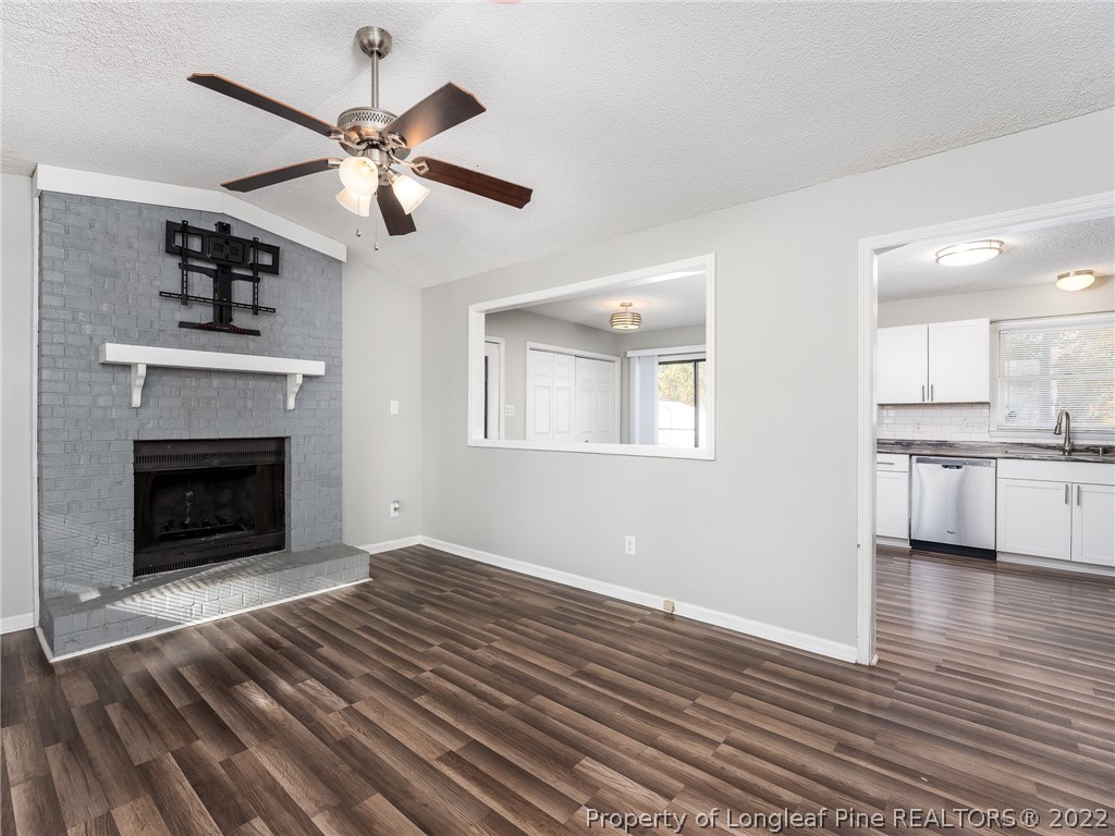 921 Hollydale Lane Fayetteville, NC 28314 - Photo 10 of 32 a view of a livingroom with a fireplace a ceiling fan and wooden floor