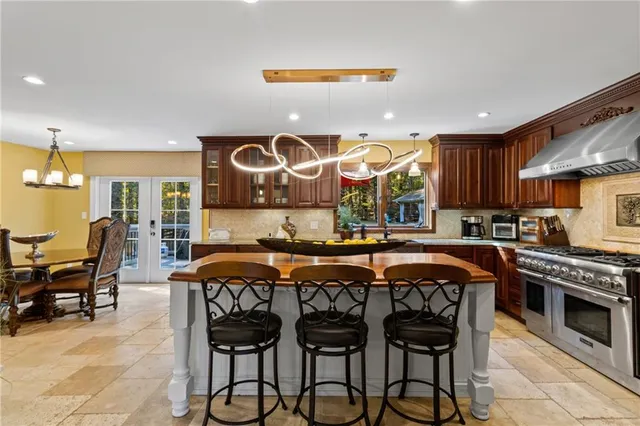 a room with stainless steel appliances kitchen island granite countertop a stove and a sink