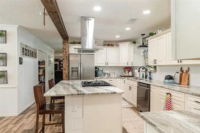 a kitchen with stainless steel appliances kitchen island granite countertop a sink stove and refrigerator
