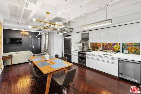 a kitchen with stainless steel appliances kitchen island granite countertop a table chairs sink and cabinets