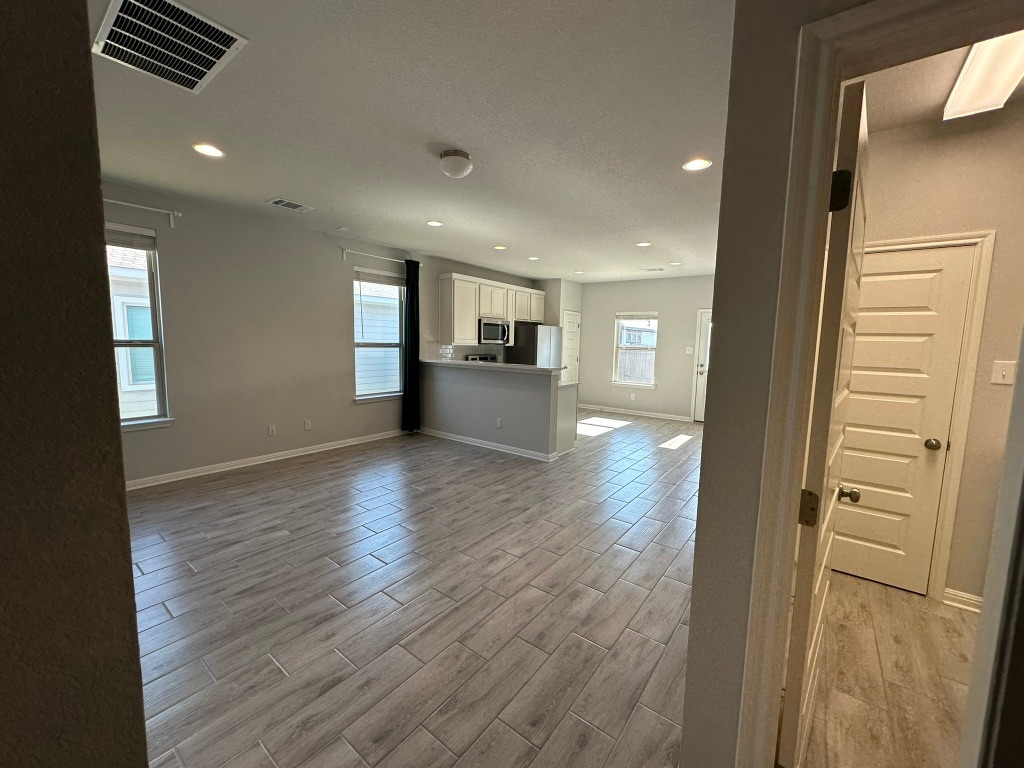 224 Wild Wind Trail Jarrell, TX 76537 - Photo 3 of 13 an empty room with wooden floor and windows