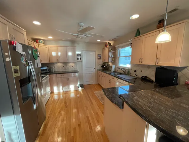 a kitchen with stainless steel appliances granite countertop a refrigerator a stove and a wooden floors