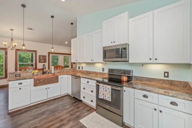 a kitchen with stainless steel appliances granite countertop a stove a sink and white cabinets