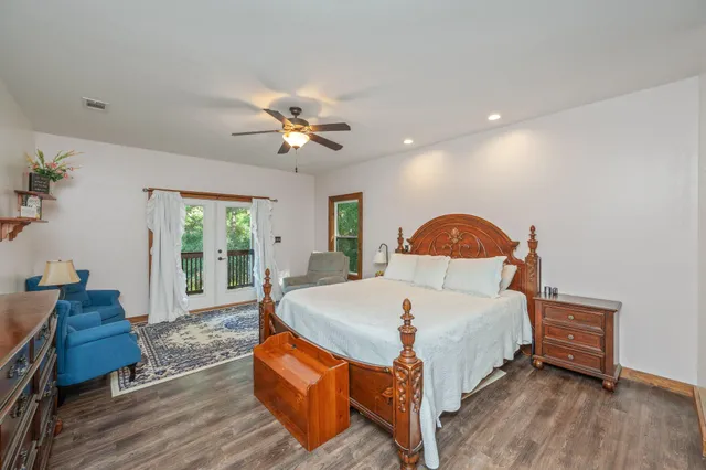 a bedroom with a bed a dresser and wooden floor