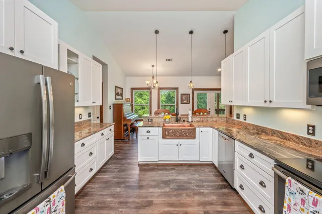 a large white kitchen with stainless steel appliances granite countertop a refrigerator a stove a sink dishwasher and white cabinets with wooden floor