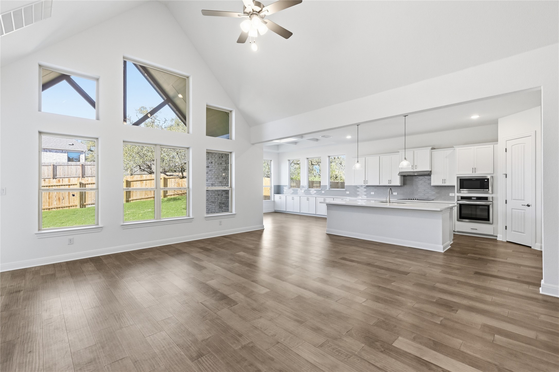 308 Frio Spgs Trail Georgetown, TX 78628 - Photo 13 of 32 a large white kitchen with kitchen island a chandelier and wooden floors