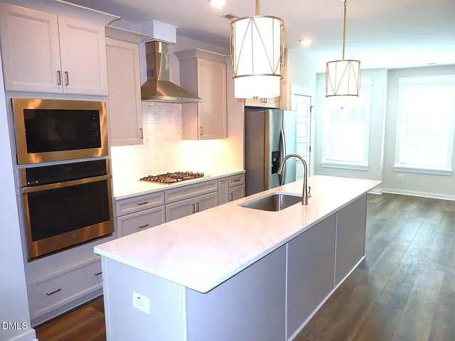 a kitchen with stainless steel appliances granite countertop a sink a stove and a refrigerator