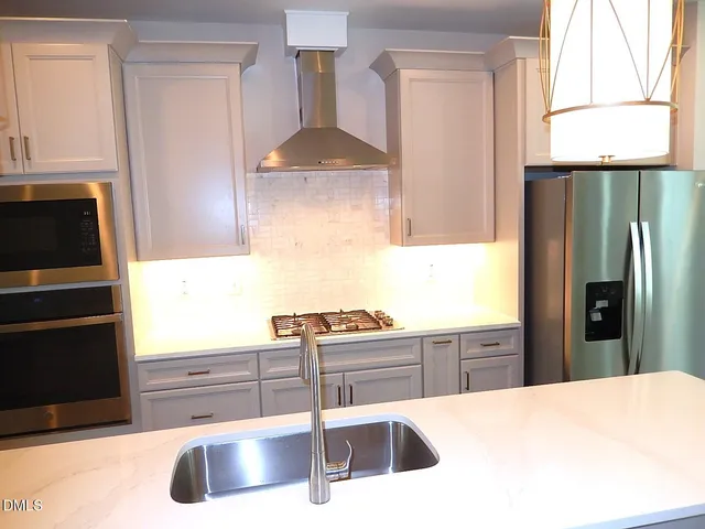 a kitchen with stainless steel appliances granite countertop a sink a stove and a refrigerator