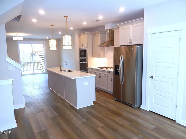 a kitchen with stainless steel appliances kitchen island granite countertop a refrigerator a sink and a oven