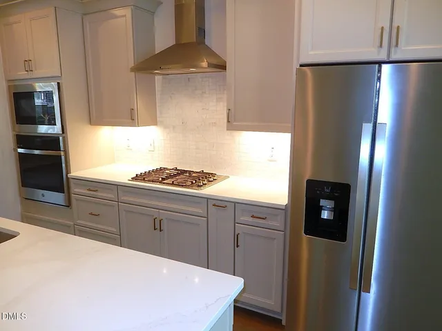 a kitchen with stainless steel appliances a refrigerator a stove and a refrigerator with wooden floor