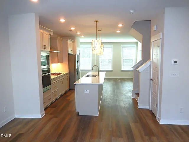 a kitchen with kitchen island wooden floors appliances and cabinets