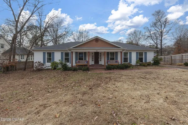a front view of a house with a garden and trees