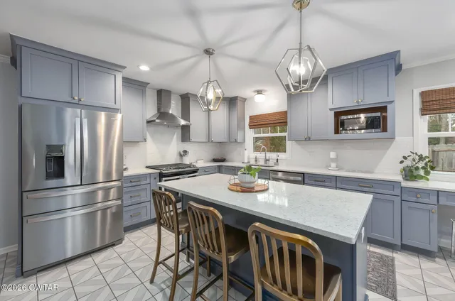 a kitchen with stainless steel appliances granite countertop a sink a stove a refrigerator cabinets a dining table and chairs