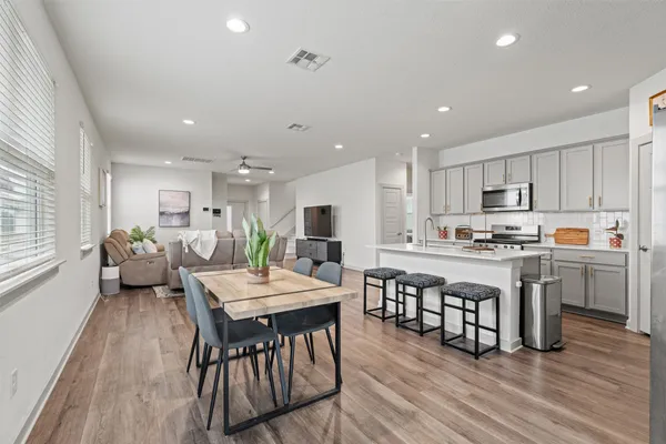 a large kitchen with kitchen island a dining table chairs and white cabinets