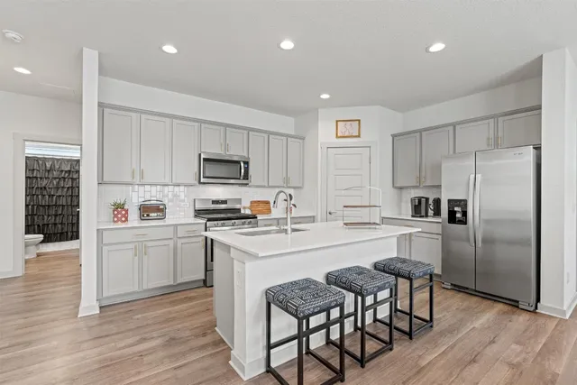 a large kitchen with kitchen island a dining table chairs and white cabinets