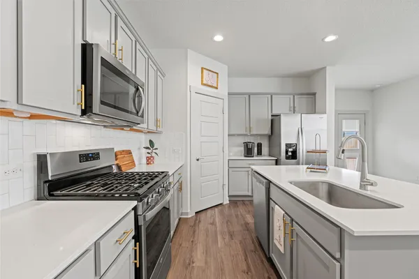 a kitchen with stainless steel appliances granite countertop a sink stove microwave and refrigerator