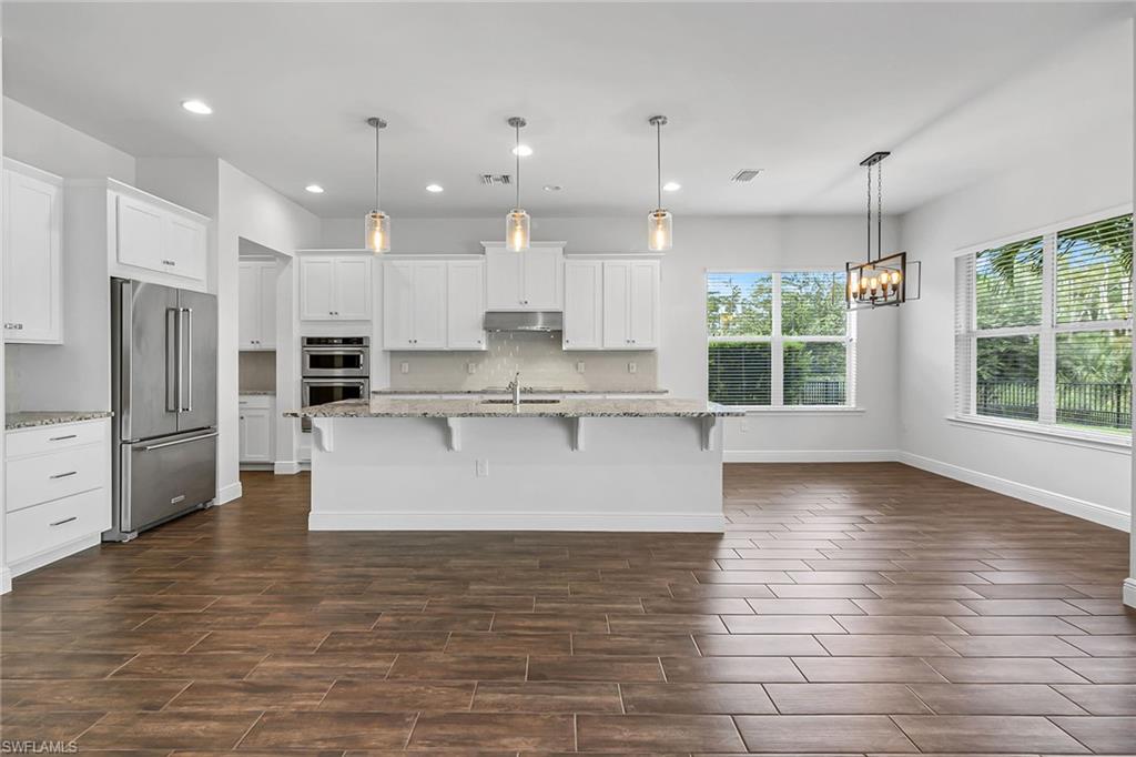 3668 Pilot Circle Naples, FL 34120 - Photo 4 of 29 a large kitchen with kitchen island a stove a refrigerator a sink dishwasher and a refrigerator with wooden floor