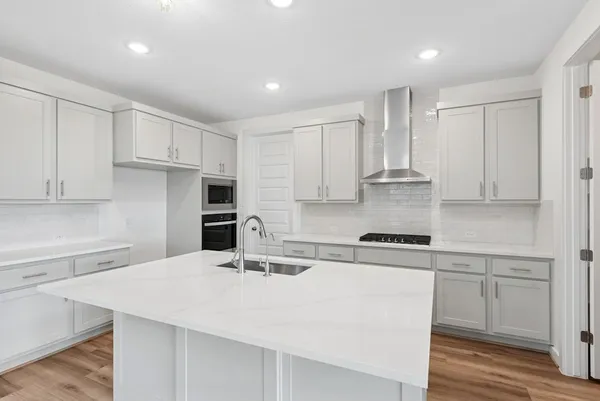a kitchen with stainless steel appliances granite countertop a sink a stove a refrigerator and white cabinets