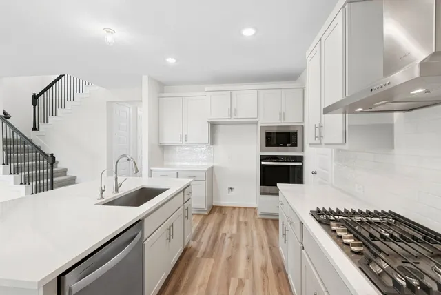 a kitchen with stainless steel appliances a sink a stove a refrigerator cabinets and a counter top space