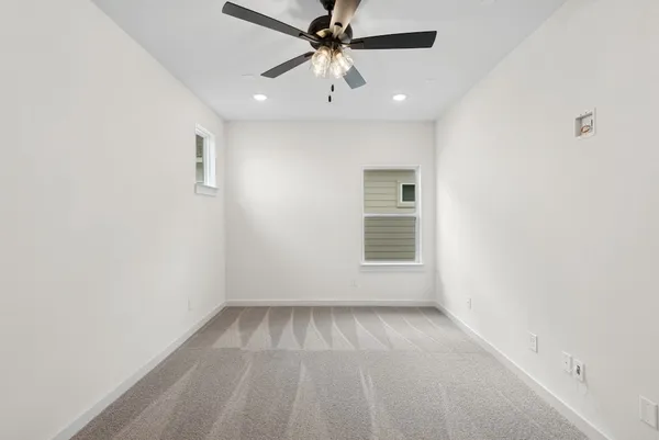 an empty room with a ceiling fan and windows