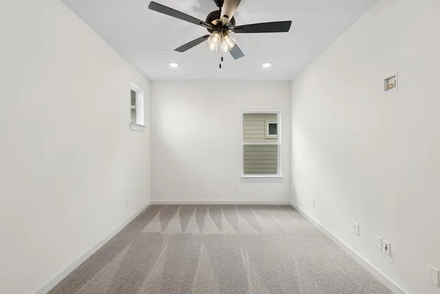 an empty room with a ceiling fan and windows