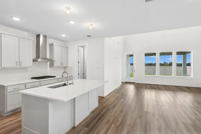 a kitchen with a sink a stove cabinets and wooden floor