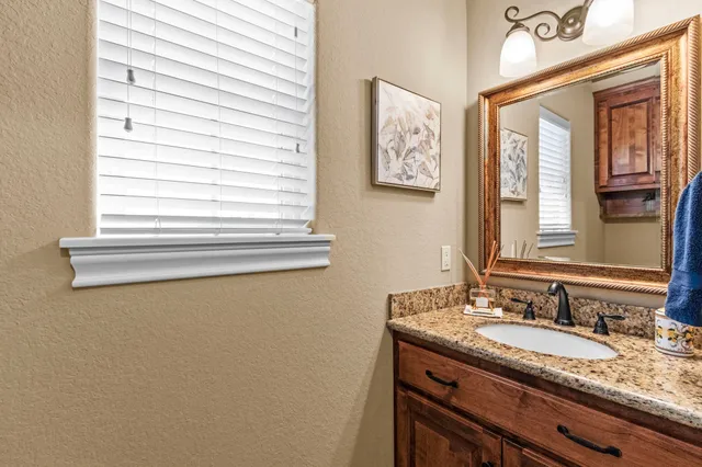 a bathroom with a granite countertop sink and a window