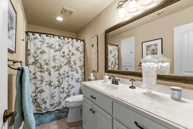 a bathroom with a granite countertop sink a toilet and a mirror