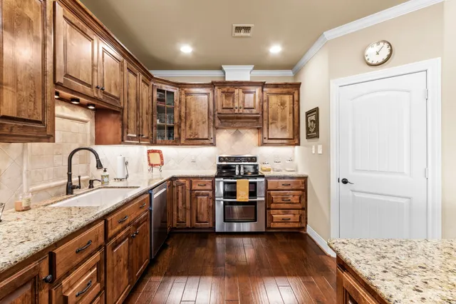 a kitchen with stainless steel appliances granite countertop wooden cabinets a stove top oven a sink and dishwasher