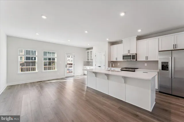 a kitchen with stainless steel appliances a stove top oven a sink a refrigerator a center island and cabinets