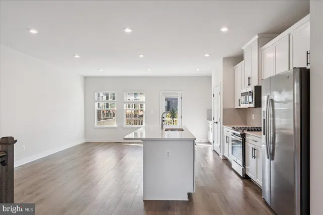 a kitchen with stainless steel appliances a refrigerator sink and wooden floor
