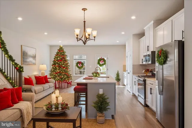 a kitchen with stainless steel appliances kitchen island granite countertop a refrigerator a stove a dining table and chairs with wooden floor