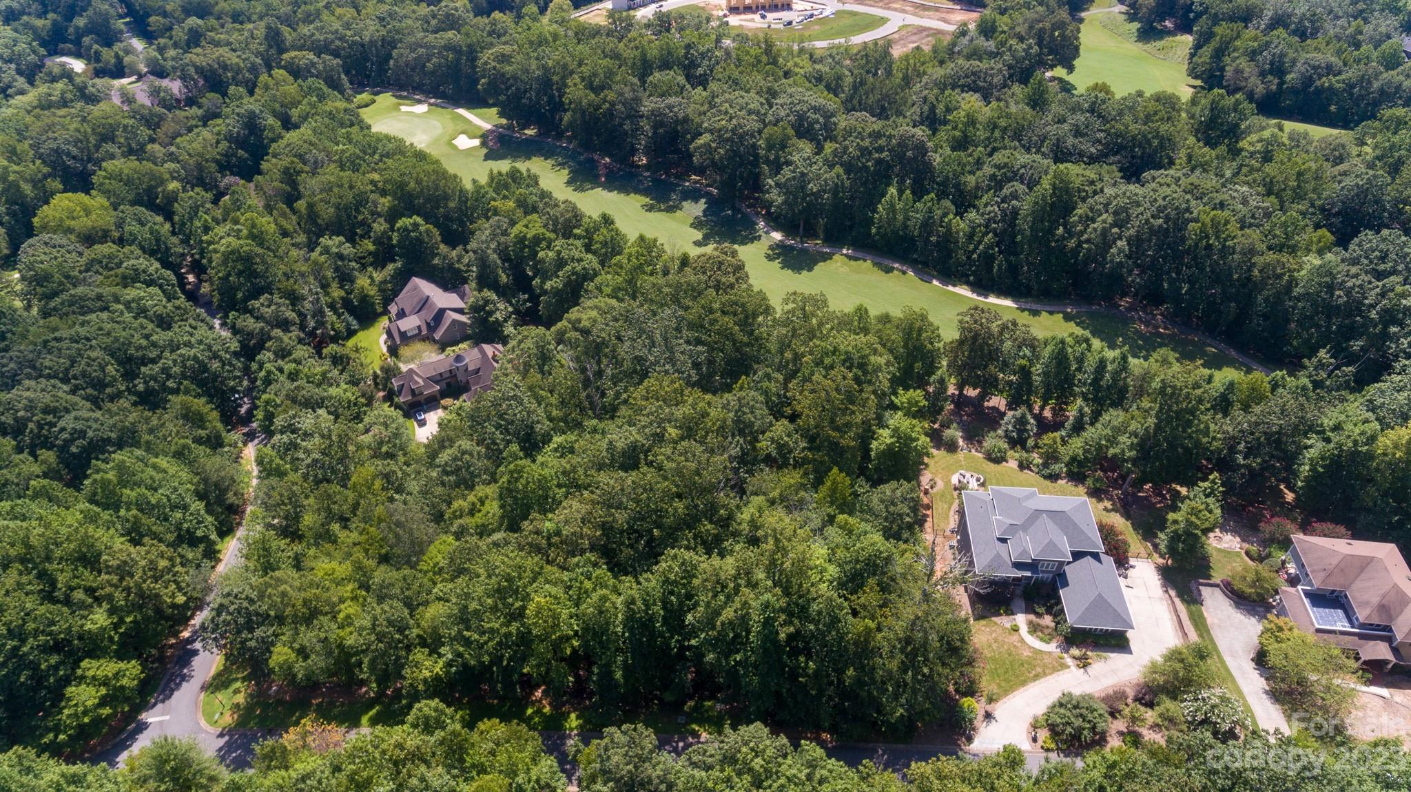 an aerial view of residential house with outdoor space and trees all around