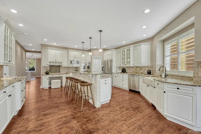 a large kitchen with white cabinets a sink dishwasher a stove a dining table and chairs