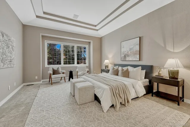 a spacious bedroom with a bed a table and painting