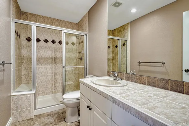 a bathroom with a granite countertop sink toilet and shower