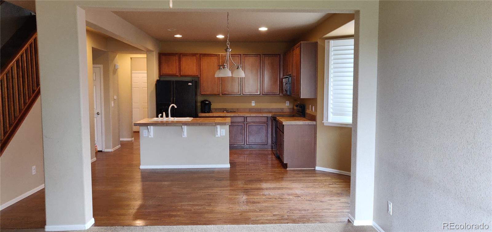 8108 Raspberry Drive Frederick, CO 80504 - Photo 8 of 16 a kitchen with kitchen island granite countertop wooden floors and wide window