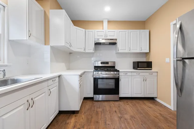 a kitchen with granite countertop white cabinets and stainless steel appliances