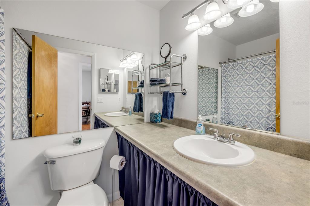 1981 South Merrick Drive Deltona, FL 32738 - Photo 16 of 30 a bathroom with a granite countertop sink a toilet a mirror and shower curtain
