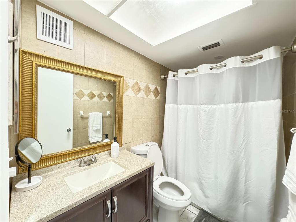 1433 South Belcher Road, Unit C1 Clearwater, FL 33764 - Photo 17 of 27 a bathroom with a granite countertop sink toilet and a mirror
