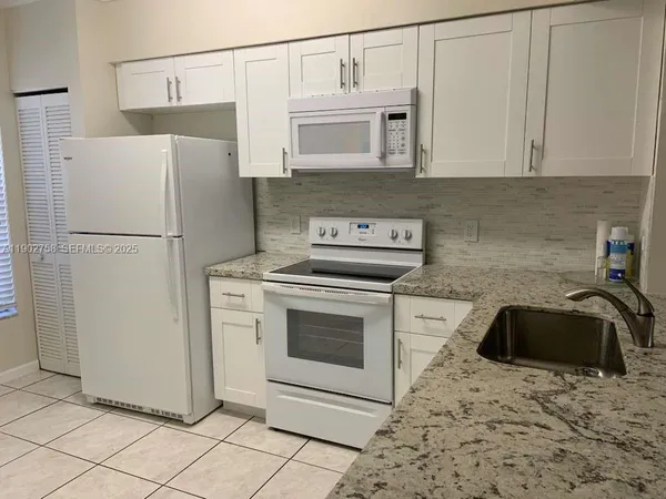 a kitchen with a refrigerator sink and cabinets