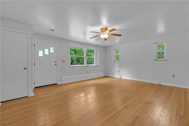 a view of an empty room with a window and wooden floor